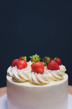 Mavi arka plan üzerinde izomalt şekil ve çilek ile dekore edilmiş kek.