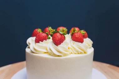 Mavi arka plan üzerinde izomalt şekil ve çilek ile dekore edilmiş kek.