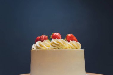 Mavi arka plan üzerinde izomalt şekil ve çilek ile dekore edilmiş kek.