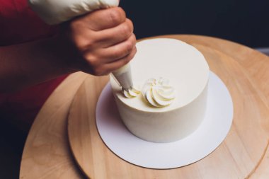 Şekerleme böğürtlen beyaz krema ile bisküvi kek ile dekore edilmiştir. Pasta ahşap bir masanın üzerinde duruyor. Ev yapımı pasta kavramı, pişirme kek.