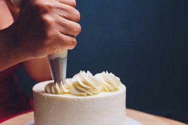 Şekerleme böğürtlen beyaz krema ile bisküvi kek ile dekore edilmiştir. Pasta ahşap bir masanın üzerinde duruyor. Ev yapımı pasta kavramı, pişirme kek.