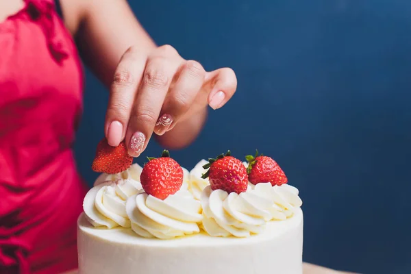 Кондитер украшен ягодами бисквитный торт с белым кремом. Торт стоит на деревянном столе. Концепция домашней выпечки, приготовления тортов . — стоковое фото
