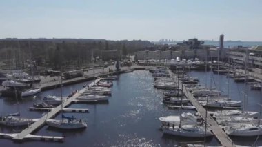 Yat Kulübü ve Marina 'nın insansız hava aracı. Yat kulübünün en iyi manzarası. Deniz suyunda beyaz kayıklar. Marina rıhtımı yatları ve küçük motorlu tekneler. Yat ve yelkenli rıhtıma demirlemiş. Otopark.