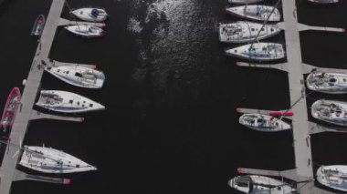 Yat Kulübü ve Marina 'nın insansız hava aracı. Yat kulübünün en iyi manzarası. Deniz suyunda beyaz kayıklar. Marina rıhtımı yatları ve küçük motorlu tekneler. Yat ve yelkenli rıhtıma demirlemiş. Otopark.