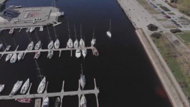 Yat Kulübü ve Marina 'nın insansız hava aracı. Yat kulübünün en iyi manzarası. Deniz suyunda beyaz kayıklar. Marina rıhtımı yatları ve küçük motorlu tekneler. Yat ve yelkenli rıhtıma demirlemiş. Otopark.