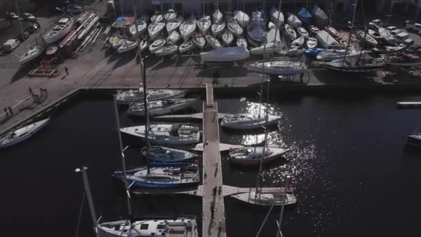 Luchtfoto door Drone van Yacht Club en Marina. Top uitzicht op de jachtclub. Witte boten in zeewater. Jachthaven jachten en kleine motorboten. Jacht en zeilboot ligt afgemeerd aan de kade. Parkeren. — Stockvideo