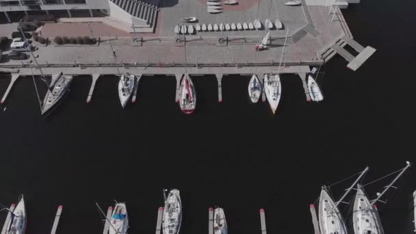 Vista aérea por Drone de Yacht Club y Marina. Vista superior del club náutico. Barcos blancos en agua de mar. Marina muelle de yates y pequeñas lanchas a motor. Yate y velero está amarrado en el muelle. Aparcamiento. — Vídeo de stock