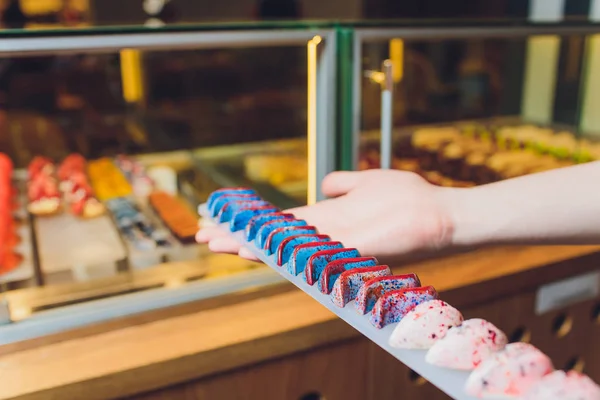 Primer plano de los vendedores manos sacando pastel de escaparate en panadería . — Foto de Stock