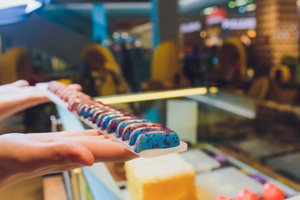 Close up of vendors hands taking out cake from showcase in bakery.