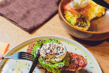 Bütün tahıl ekmeği sandviç kızarmış bıldırcın yumurta, avokado, otlar ve tohumlar siyah arka plan üzerinde. Temiz yemek, sağlıklı vejetaryen kahvaltı.