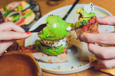 Bütün tahıl ekmeği sandviç kızarmış bıldırcın yumurta, avokado, otlar ve tohumlar siyah arka plan üzerinde. Temiz yemek, sağlıklı vejetaryen kahvaltı.