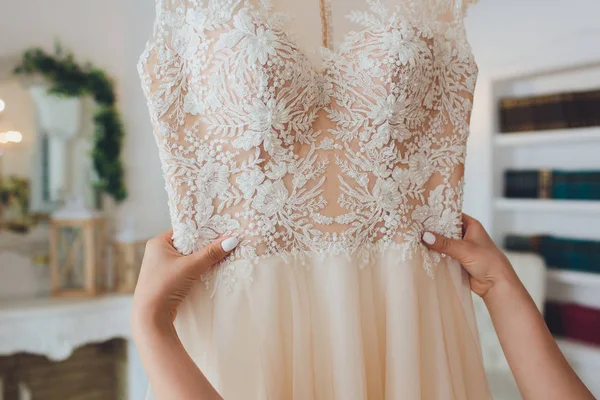 Gazdag rózsaszín menyasszonyi ruha lóg a csillár egy fehér szobában. — Stock Fotó