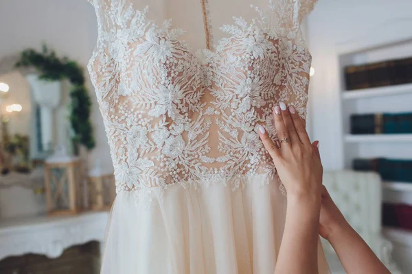 Vestido de noiva rosa rico pendura em um lustre em uma sala branca . — Fotografia de Stock