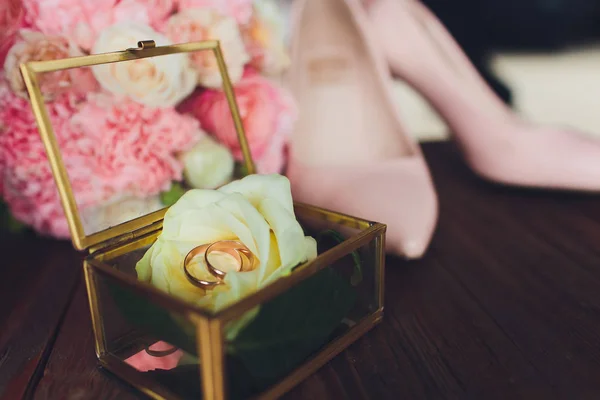 wedding rings in the box and a bouquet of the bride on the table.