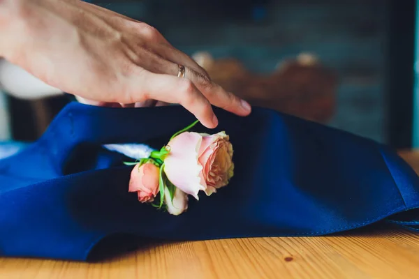 Рука цепляется за жениха бутоньерка настоящих цветов . — стоковое фото