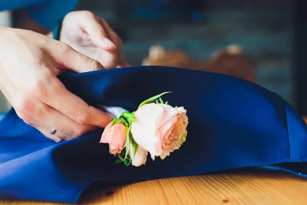 hand clings to the bridegroom a boutonniere of real flowers.