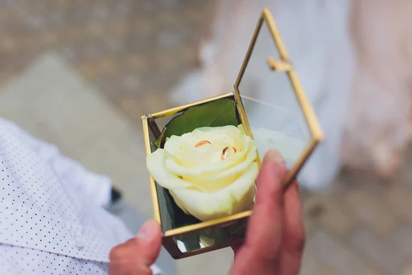 Свадебные кольца в коробке и букет невесты в руке . — стоковое фото