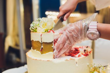Üç katmanlı beyaz düğün pastası mastik Beyaz ahşap bir masa üzerinde çiçek ile dekore edilmiştir. Bir menü veya bir şekerleme kataloğu ile kopya alanı için resim.