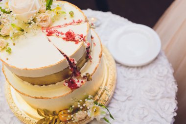 Üç katmanlı beyaz düğün pastası mastik Beyaz ahşap bir masa üzerinde çiçek ile dekore edilmiştir. Bir menü veya bir şekerleme kataloğu ile kopya alanı için resim.