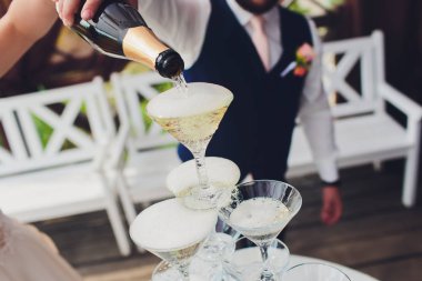 Şampanyalı şarap kadehleri piramidi. Şampanya bardaklara dökülür. Şampanya bardakları bir piramit ile olayın şenlikli dekorasyon. Sıçrama ve damla.