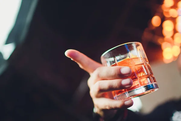 Whisky o cola con ghiaccio. Il vetro nella mano maschile è una vista dall'alto. Sfondo scuro . — Foto Stock