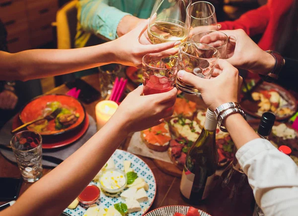 Menselijke handen met glazen rode wijn rammelende ze boven tafel geserveerd. — Stockfoto