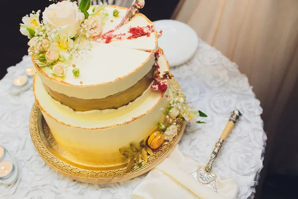 Трехъярусный белый свадебный торт, украшенный цветами из мастики на белом деревянном столе. Изображение для меню или каталога кондитерских изделий с копировальным пространством . — стоковое фото