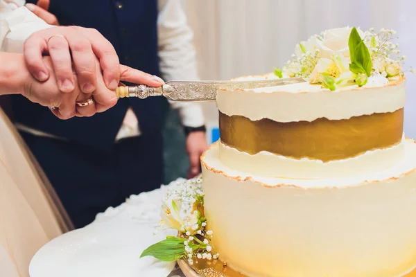 Трехъярусный белый свадебный торт, украшенный цветами из мастики на белом деревянном столе. Изображение для меню или каталога кондитерских изделий с копировальным пространством . — стоковое фото