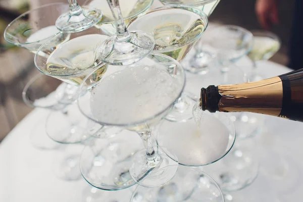 Pirámide de copas de vino con champán. El champán se vierte en las copas. Decoración festiva del evento con una pirámide de copas de champán. Salpicadura y gotas . —  Fotos de Stock