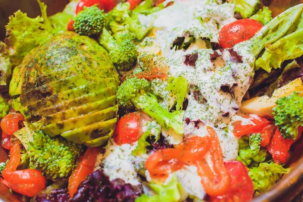 아보카도, 오이, 체리 토마토, 차드 잎, 브로콜리를 곁들인 야채 샐러드를 나무 테이블에 얹어 놓습니다.. — 스톡 사진