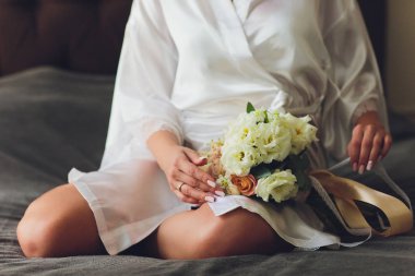 Güller ile gelinin elinde güzel düğün buketi. Düğün günü. Bokeh. Gelin. Gelinler buketi. Düğün çiçekleri. Buket bir broş ile dekore edilmiştir.