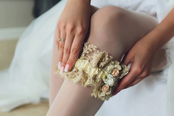 Vestidos de noiva liga na perna. Imagem de belas pernas descalças femininas em vestido de noiva. A noiva veste meias em pernas. Noiva colocando uma liga de casamento em sua perna . — Fotografia de Stock
