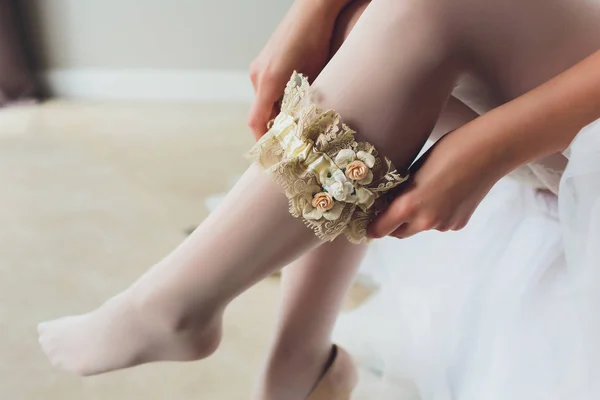 Vestidos de noiva liga na perna. Imagem de belas pernas descalças femininas em vestido de noiva. A noiva veste meias em pernas. Noiva colocando uma liga de casamento em sua perna . — Fotografia de Stock