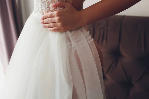 Closeup toned photo of beautiful bride tying up her wedding dress. — Stock Photo, Image