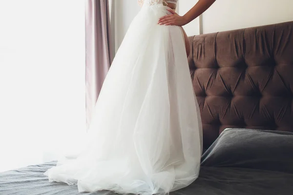 Closeup toned photo of beautiful bride tying up her wedding dress. — Stock Photo, Image