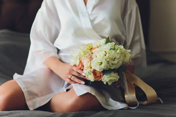 Belo buquê de casamento nas mãos da noiva com rosas. Dia do casamento. Bokeh. Noiva. Buquê de noivas. Flores de casamento. O buquê é decorado com um broche . — Fotografia de Stock