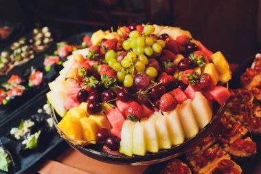 karışık taze meyve çilek, ahududu, yaban mersini, kivi, ahşap kase üzerinde mango.