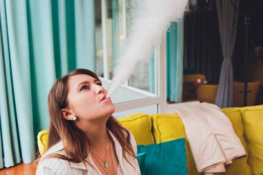 Restoranın yaz terasında güzel esmer duman elektronik sigara.