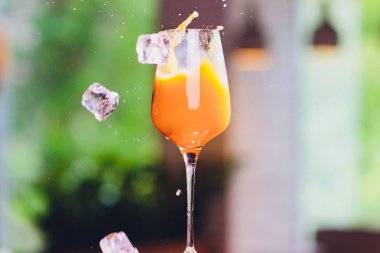 buz küpleri bir sıçrayan portakal kokteyl içine düşen.
