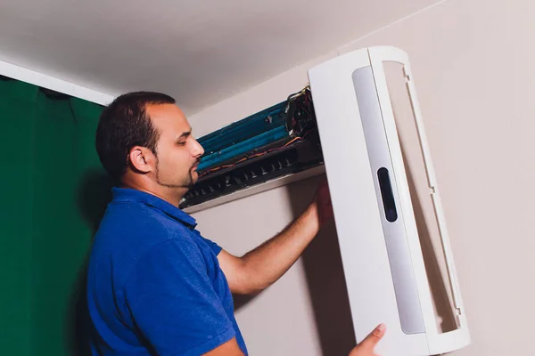 Male technician cleaning air conditioner indoors. service