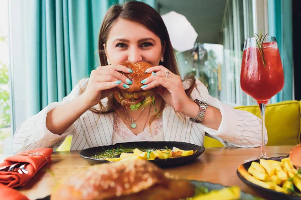 Giovane donna che mangia hamburger vegetariano. Vista posteriore . — Foto Stock