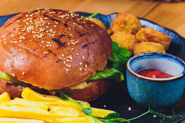 Vegetarian lentil burger in wholewheat bun with lettuce, tomato and cucumber accompanied by French fries Selective Focus, Focus on the front of the sandwich.