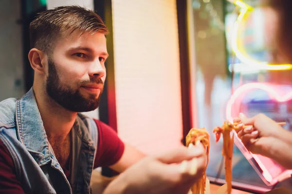 Concepto de comida callejera. Fideos japoneses chinos con pollo y verduras en utensilios de papel desechables. Espacio de copia, enfoque selectivo. sobre el fondo de una lámpara de neón en forma de corazón . — Foto de Stock