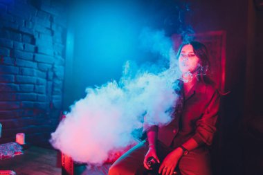 kadın odada yatakta yatan bir e-sigara içiyor. Sigara içenler kavramı Vaping.