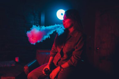 kadın odada yatakta yatan bir e-sigara içiyor. Sigara içenler kavramı Vaping.