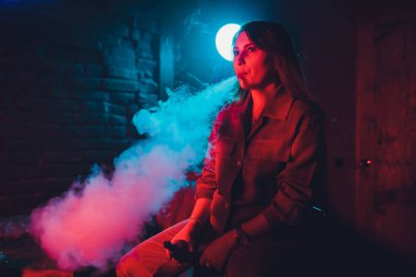 kadın odada yatakta yatan bir e-sigara içiyor. Sigara içenler kavramı Vaping.
