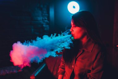 kadın odada yatakta yatan bir e-sigara içiyor. Sigara içenler kavramı Vaping.