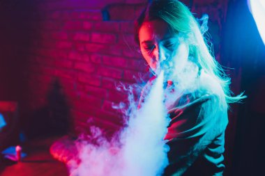 kadın odada yatakta yatan bir e-sigara içiyor. Sigara içenler kavramı Vaping.