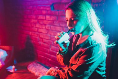 kadın odada yatakta yatan bir e-sigara içiyor. Sigara içenler kavramı Vaping.