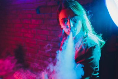 kadın odada yatakta yatan bir e-sigara içiyor. Sigara içenler kavramı Vaping.